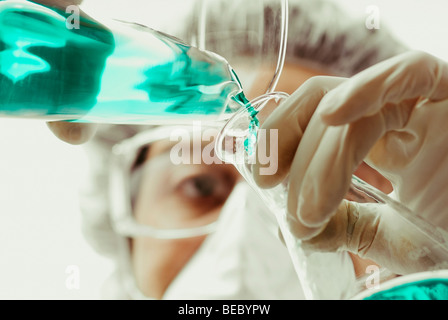 Wissenschaftler, die Flüssigkeit in eine konische Kanne gießen Stockfoto