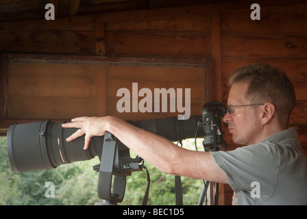 Männliche Naturfotograf mit Teleobjektiv in Vogel verstecken Stockfoto