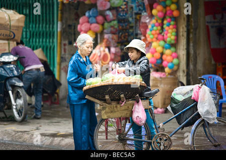 Eine Frau verkauft Gemüse aus dem Fahrrad in Vietnam in Hanoi Stockfoto