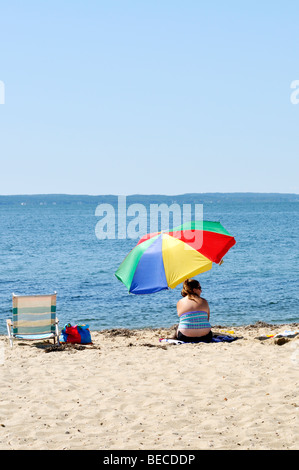 Frau am Strand von Cape Cod unter bunten Regenschirm an einem sonnigen Sommertag. Stockfoto