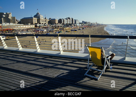 Liegestuhl auf De Scheveningse Pier, Blick über den Strand in Richtung das Steigenberger Kurhaus Hotel in Scheveningen, eine anspruchsvolle Stockfoto