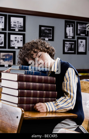Schuljunge schlafen auf Bücher in einem Klassenzimmer Stockfoto