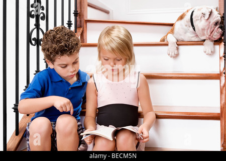 Junge und ein Mädchen sitzt auf einer Treppe und liest ein Buch Stockfoto