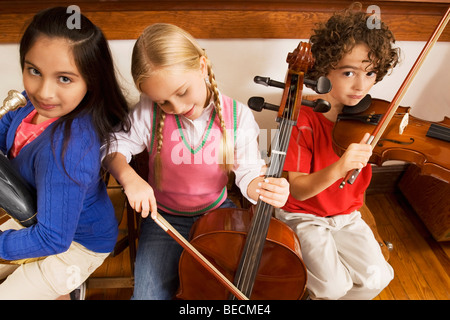 Drei Studenten spielen Musikinstrumente in einem Klassenzimmer Stockfoto