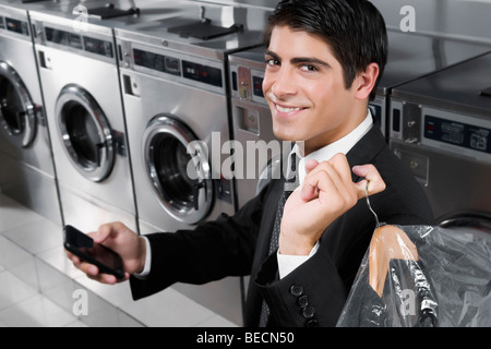 Geschäftsmann SMS auf ein Handy in einem Waschsalon Stockfoto