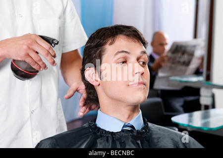 Barbier sprühen Wasser auf das Haar des Mannes Stockfoto