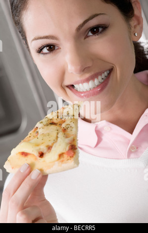 Porträt von Köchin halten ein Pizzastück Stockfoto