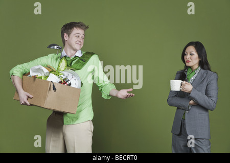 Geschäftsmann hält seine Habseligkeiten und eine Geschäftsfrau hält eine Tasse Kaffee Stockfoto