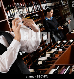 Kellner, Polieren, ein Glas Wein und eine Geschäftsfrau, wählen Sie eine Flasche in einer bar Stockfoto