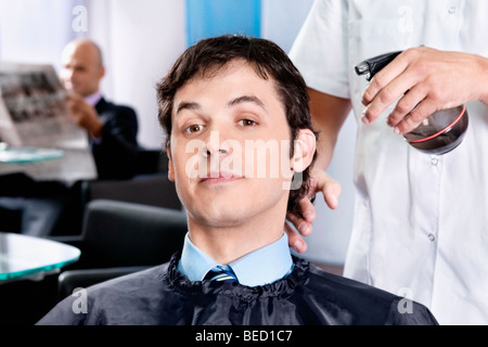 Barbier sprühen Wasser auf das Haar des Mannes Stockfoto