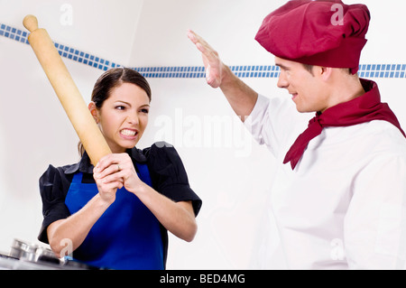 Weibliche und männliche Koch in der Küche kämpfen Stockfoto