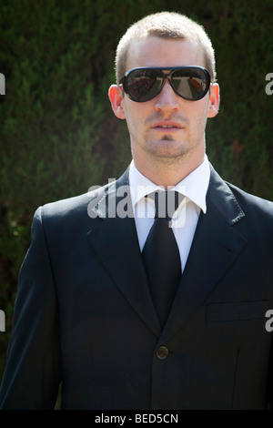 Gut aussehend Geschäftsmann schaut in die Kamera durch Sonnenbrillen Stockfoto