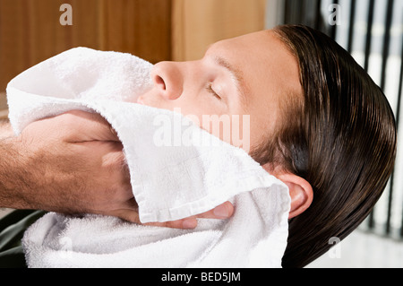 Barber Gesicht eines Mannes mit einem Tuch abwischen Stockfoto