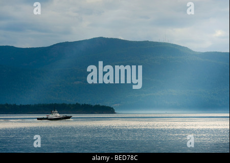 Ein Schlepper macht seinen Weg in Richtung Vancouver, Kanada durch Rosario Strait und vorbei an Lummi Island. Orcas Island im Hintergrund. Stockfoto