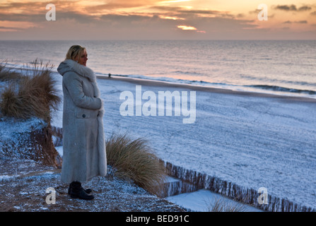 Winter auf der Insel Sylt, Frau den Sonnenuntergang im stehen am Rotes Kliff, Kampen, Sylt, Nordfriesischen Inseln, Schleswig-Holstein Stockfoto