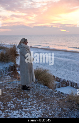 Winter auf der Insel Sylt, Frau den Sonnenuntergang im stehen am Rotes Kliff, Kampen, Sylt, Nordfriesischen Inseln, Schleswig-Holstein Stockfoto