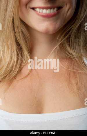 Das Lächeln und die Brust einer jungen blonden Frau in einem weißen Hemd. Stockfoto