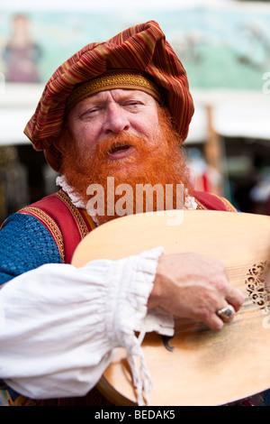 Mann im Kostüm spielt musikalische Saiteninstrument während Renaissance Festival in Zentral-Florida, USA Stockfoto