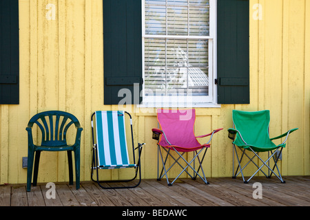 Vielzahl von bunten Strandkörbe auf hölzernen Veranda von hellen gelben Gebäude. Stockfoto