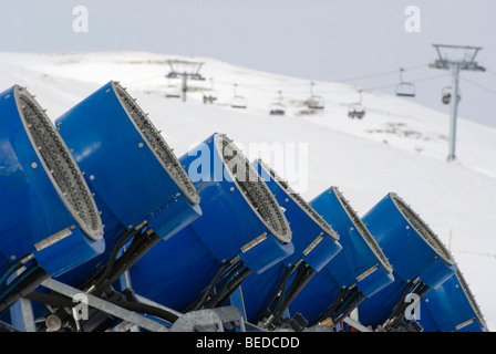 Schneekanonen stehen in einer Reihe am Rand der Piste vor einem Sessellift, Graubündens, der Schweiz, Europa Stockfoto