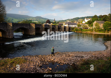 Die alte Brücke über den Fluss Usk in Crickhowell, Powys Mid Wales UK, mit dem Tafelberg in der Ferne und ein Mann Angeln Stockfoto