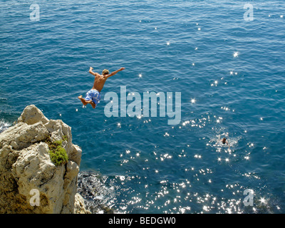 Ein Mann taucht von einer Klippe ins Meer in Antibes an der Cote d ' Azur in Südfrankreich Stockfoto