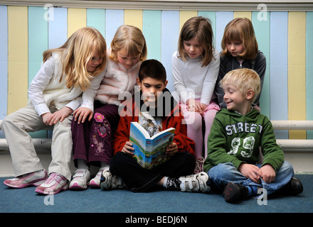 EINE GRUPPE VON VIER MÄDCHEN UND ZWEI JUNGEN, DIE ZUSAMMEN EINE BIBEL ZU LESEN, AN EINEM SONNTAG SCHOOL UK Stockfoto