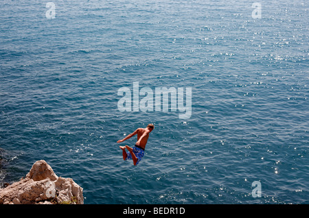 Ein Mann taucht von einer Klippe ins Meer in Antibes an der Cote d ' Azur in Südfrankreich Stockfoto