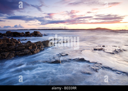 Sonnenuntergang mit Blick auf Holyhead Mountain gesehen hier von Porth Penrhyn-Mawr auf die Isle OF Anglesey. Stockfoto