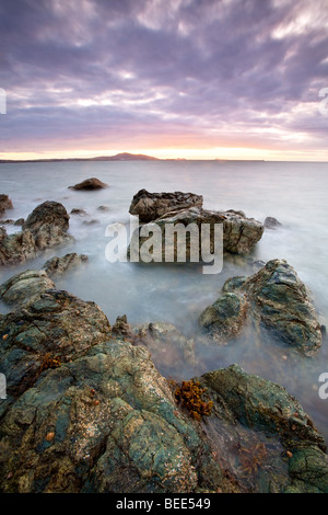 Sonnenuntergang mit Blick auf Holyhead Mountain gesehen hier von Porth Penrhyn-Mawr auf die Isle OF Anglesey. Stockfoto