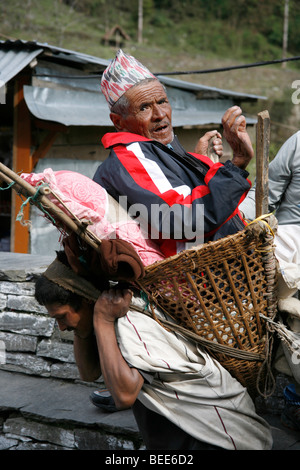 Annapurnas, Nepal - 5. April 2008. Nepali Greis durchgeführt von Porter in sein Dorf Stockfoto