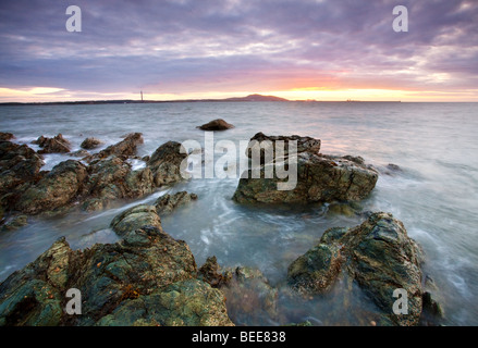 Sonnenuntergang mit Blick auf Holyhead Mountain gesehen hier von Porth Penrhyn-Mawr auf die Isle OF Anglesey. Stockfoto