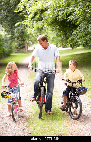 Vater und Kinder Reiten Fahrräder in Landschaft Stockfoto