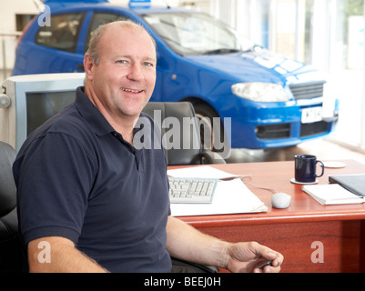 Autoverkäufer sitzen im Showroom lächelnd Stockfoto