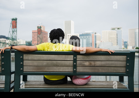 Paar, sitzen auf der Bank mit Blick auf Stadtbild Stockfoto