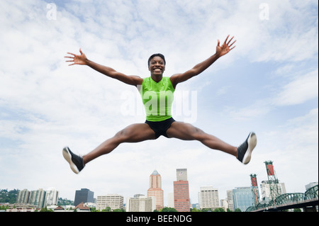 Afrikanische Frau springen mit Stadt im Hintergrund Stockfoto