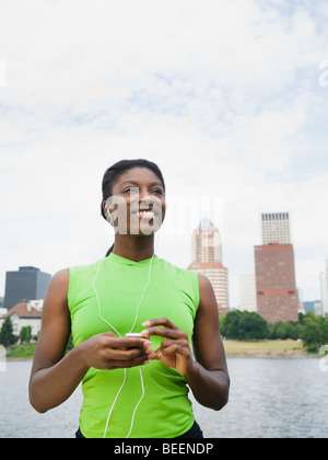 Afrikanische Frau hören Kopfhörer mit Stadt im Hintergrund Stockfoto
