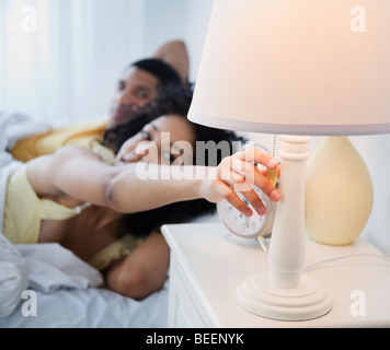 Frau im Bett erreichen Nachttischlampe deaktivieren Stockfoto