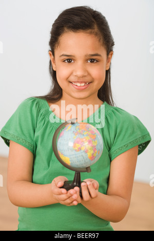 Hispanischen Mädchen halten kleine Weltkugel Stockfoto