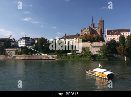 Wasser-Taxi (Seilfähre) überqueren den Rhein, Basel mit Basler Münster Kathedrale im Hintergrund, an einem Sommertag Stockfoto