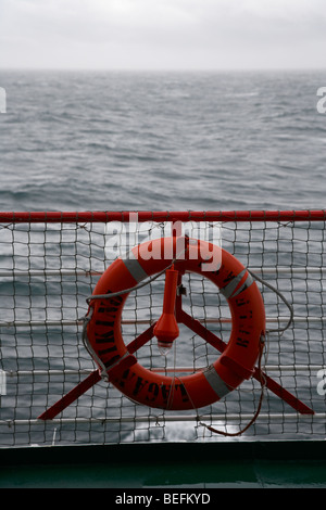 Rettungsring und Geländer an Bord der Mersey Viking Belfast Liverpool Fähre an einem stumpfen grauen Tag mit Seegang Stockfoto