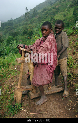 Bakonzo Jungen spielen mit ihren hölzernen Fahrrad im Regen, Ruwenzori-Gebirge, West-Uganda, Afrika Stockfoto