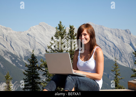 Junge Frau mit einem Laptop in den Bergen Stockfoto