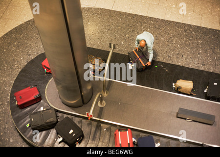 Flugpassagiere packt seinen Koffer aus dem Karussell in der Gepäckhalle Rückforderung in der Ankunftshalle des Flughafens Heathrow T5 Stockfoto