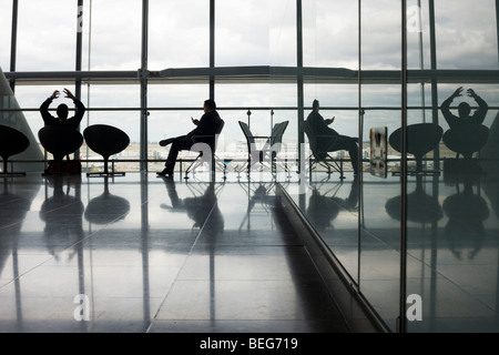Die Silhouetten der abfliegenden Passagiere gegen die starken Tageslicht aus den großen Fenstern des Heathrow Terminal 5 Stockfoto