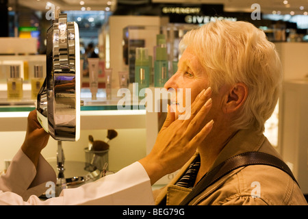 Eine ältere Dame erhält eine Beratung von professionellen Kosmetikerin in Clinique Bar am World Duty Free im Flughafen Heathrow T5 Stockfoto