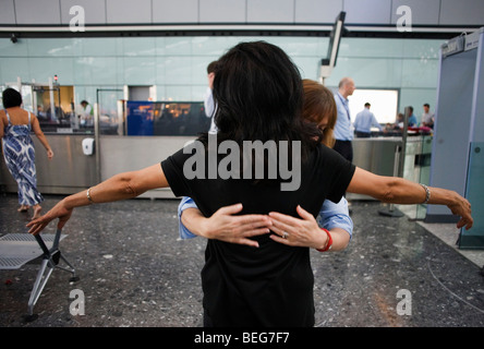 Weibliche operative Sicherheit fühlt sich um eine Dame Passagier zurück nach verdächtigen Elementen während der Suche am Flughafen Heathrow T5 Stockfoto