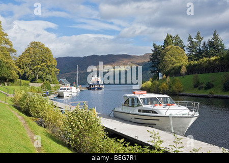 Motorschiffe Vergnügen vor Anker am Caledonian Canal in Fort Augustus mit Herrn der Glens und Loch Ness im Hintergrund Stockfoto