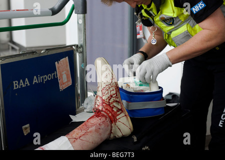 Ein NHS-Sanitäter-Responder besucht Lady Passagier in Heathrows terminal 3, stolperte und schlecht gashed ihr Bein hat. Stockfoto