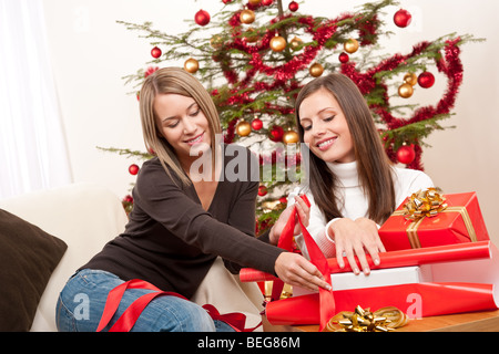 Zwei Frauen packen Weihnachtsgeschenk vor Baum Stockfoto